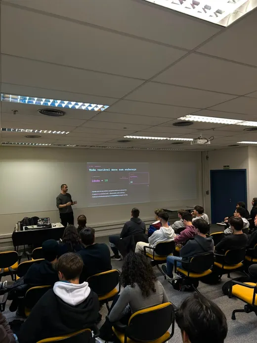 Coordenador da Liga de Algoritmos apresentando aula com slide "Toda variável mora num endereço" projetado